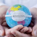 closeup of a caucasian doctor man holding a world globe with a protective mask with the word coronavirus written in it