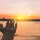 Woman hands reach out to the sky like praying in front of sky background.