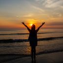 Silhouettes  of Woman raise hands up to the sunrise sky at the b