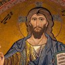 Gesù, con i capelli lunghi e la barba, benedice con la mano destra. Nellaa sinistra ha la un libro. Gesù è vestito di azzurro e oro. Lo sfondo è dorato.