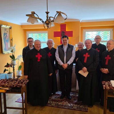 Sei uomini posano per una foto. Cinque hanno un abito nero da prete con una croce rossa sul petto. La stanza ha paeti gialle e un soffitto bianco. Sulla destra c'è una statua di San Camillo