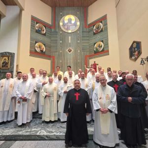 Gruppo di religiosi sull'altare di una chiesa. Alcuni sono vestiti con la tunica bianca, altri hanno una tunica nera con una croce rossa sul petto tipica dei camilliani. Alle loro spacce c'è una grande croce verde