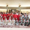Un gruppo di suore e di preti sono davanti all'altare di una chiesa per una foto. La suore sono vestite di bianco o di grigio e hanno un a croce rossa sul petto. Alcuni preti hanno una stola rossa, altri hanno un abito rosso da cerimonia