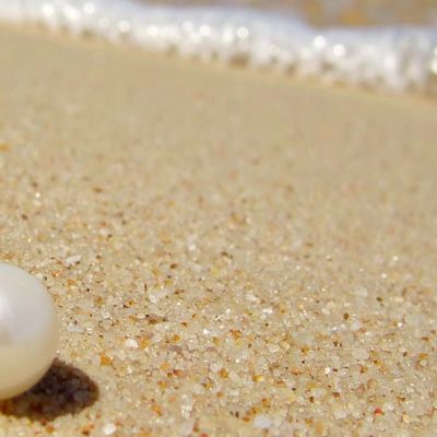 Una perla bianca si trova sulla sabbia gialla