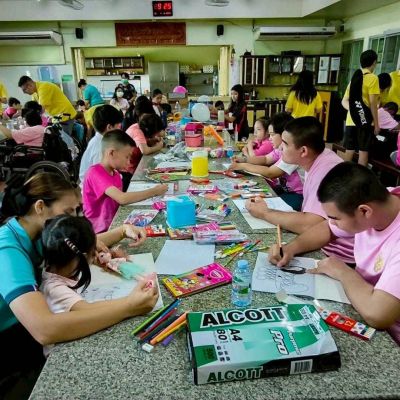 Nella foto ci sono ragazzi e ragazze che dipingono. Sono seduti a un tavolo all'interno di una stanza verde