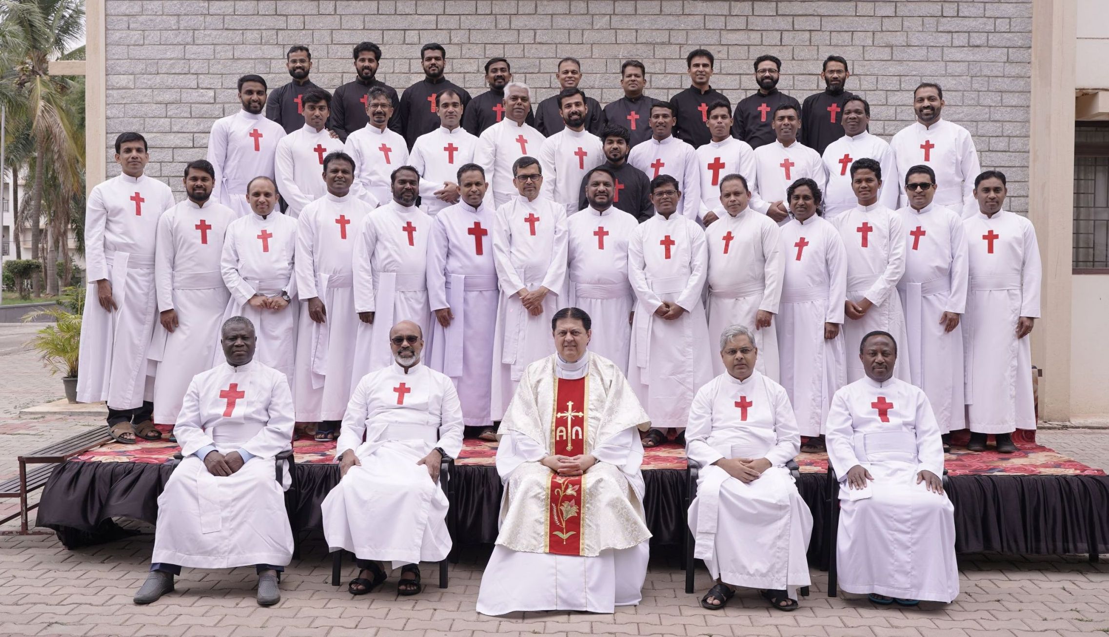 gruppo di uomini vestiti con aniti sacerdotali bianchi con la croce rossa di san Camillo