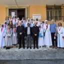 Un gruppo di persone, in maggioranza suore vestite di binaco con kla croce rossa di San Camillo, posano su una scalinata per una foto. Sullo sfondo c'è un muro giallo e delle finestre.