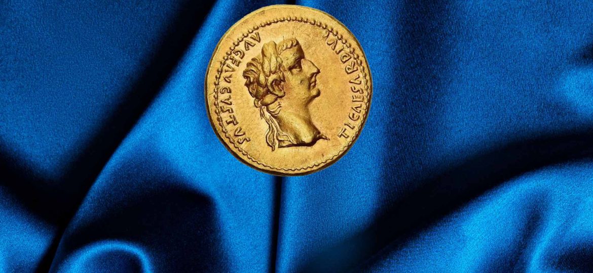 Una moneta romana del tempo dell'imperatore Tiberio è posata su un tessuto blu
