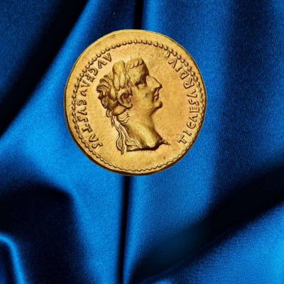 Una moneta romana del tempo dell'imperatore Tiberio è posata su un tessuto blu